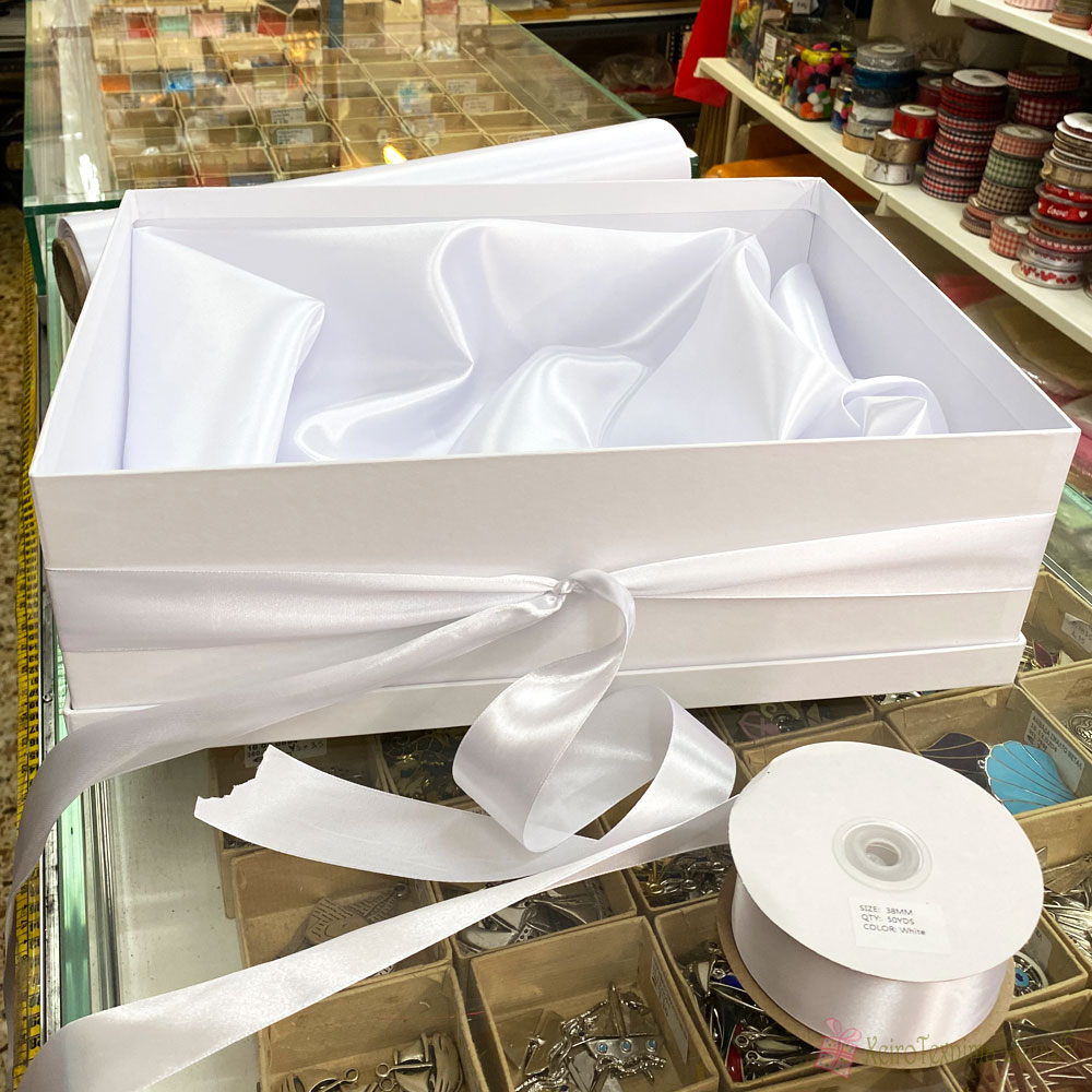 Δέσιμο κουτιού με λευκή σατέν κορδέλα για τα παπούτσια της νύφης