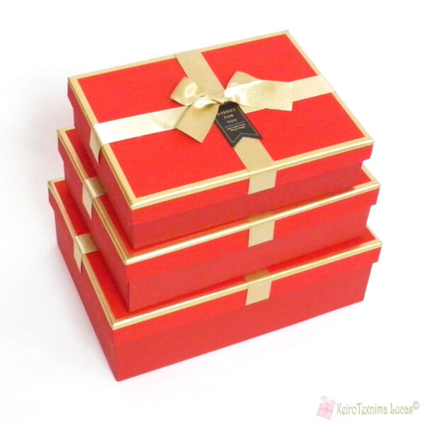 Κόκκινα παραλληλόγραμμα κουτιά με χρυσή κορδέλα σε χρυσό καπάκι